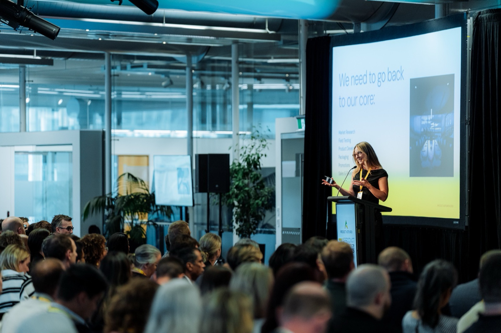 Corinna at the podium in front of a large audience